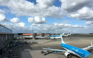 Aviones de KLM y otras aerolíneas estacionados en las puertas junto a la terminal del aeropuerto de Ámsterdam-Schiphol bajo un cielo nublado