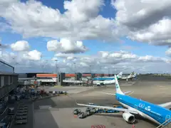 Aviones de KLM y otras aerolíneas estacionados en las puertas junto a la terminal del aeropuerto de Ámsterdam-Schiphol bajo un cielo nublado