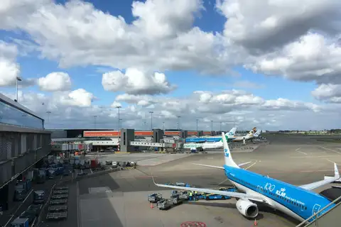 Aviones de KLM y otras aerolíneas estacionados en las puertas junto a la terminal del aeropuerto de Ámsterdam-Schiphol bajo un cielo nublado