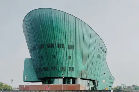 Fachada verde de cobre del museo de ciencia NEMO, con forma de casco de barco, junto al agua en Ámsterdam