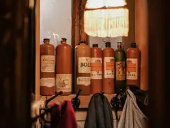 Botellas tradicionales de gres de jenever con etiquetas antiguas alineadas en una repisa de madera de un café de Ámsterdam