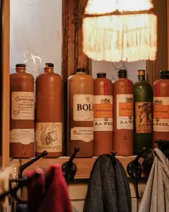 Botellas tradicionales de gres de jenever con etiquetas antiguas alineadas en una repisa de madera de un café de Ámsterdam