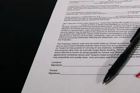 Primer plano de un contrato de alquiler impreso con las líneas de firma de arrendador e inquilino y un bolígrafo negro encima