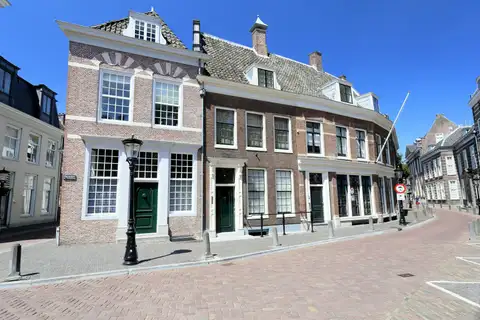 Fachadas de ladrillo con grandes ventanas blancas de cristales y puertas verdes en una calle empedrada del centro de Utrecht