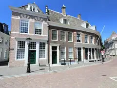 Fachadas de ladrillo con grandes ventanas blancas de cristales y puertas verdes en una calle empedrada del centro de Utrecht