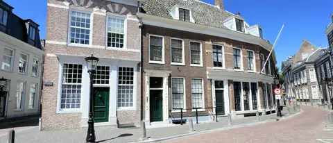 Fachadas de ladrillo con grandes ventanas blancas de cristales y puertas verdes en una calle empedrada del centro de Utrecht