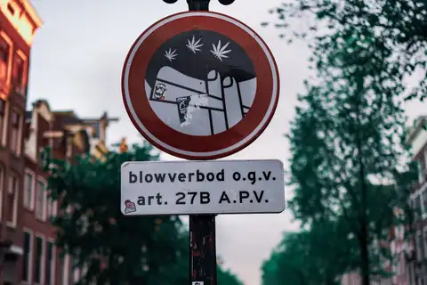 Señal municipal de prohibición de fumar cannabis (blowverbod) en un farol junto a un canal del Barrio Rojo de Ámsterdam