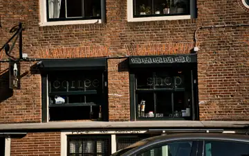 Fachada de ladrillo rojo de un coffeeshop con rótulo «coffee shop» en las ventanas, en un edificio histórico de Ámsterdam