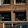 Fachada de ladrillo rojo de un coffeeshop con rótulo «coffee shop» en las ventanas, en un edificio histórico de Ámsterdam