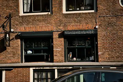 Fachada de ladrillo rojo de un coffeeshop con rótulo «coffee shop» en las ventanas, en un edificio histórico de Ámsterdam