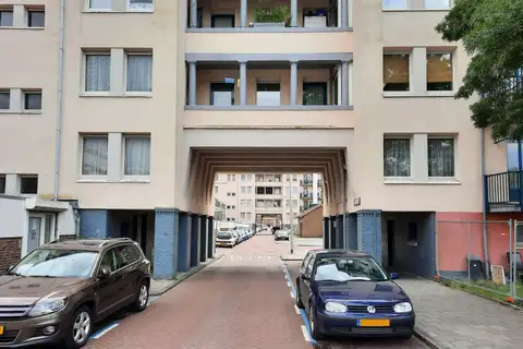 Calle residencial de ladrillo en Ámsterdam con coches aparcados en plazas marcadas con líneas azules a ambos lados