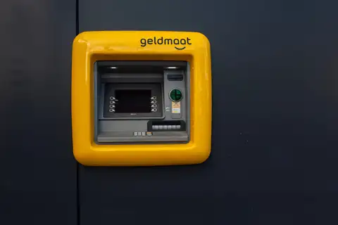 Cajero automático de Geldmaat con marco amarillo empotrado en una pared oscura en los Países Bajos