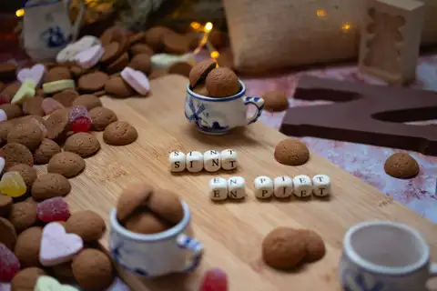 Pepernoten, caramelos de corazón y tacitas azules de Delft sobre una tabla, con una letra de chocolate y un molde de madera con un molino