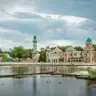 Edificios de estilo árabe con cúpulas turquesa y minarete junto al estanque del parque Efteling, con una rana gigante en el agua