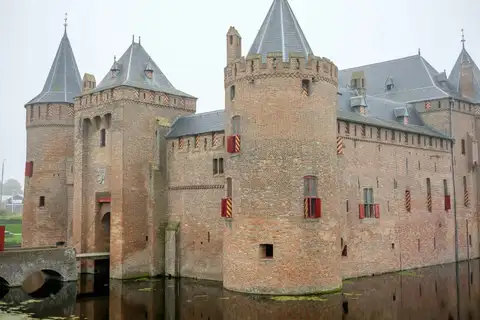 Castillo medieval de ladrillo con torres redondas y foso, el Muiderslot, junto al agua en Muiden