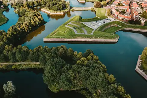 Vista aérea de los baluartes y fosos de la fortaleza estrellada de Naarden-Vesting, con casas de tejado rojo al fondo