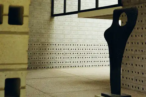 Escultura negra de formas abstractas bajo una gran ventana y muros de bloques de hormigón en el Museo Kröller-Müller
