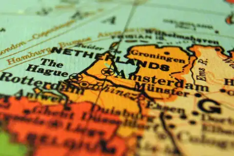 Detalle de un mapa antiguo con los Países Bajos en naranja, con Ámsterdam, La Haya, Róterdam y Groninga, y enfoque selectivo