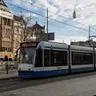 Tranvía azul y blanco de GVB frente a la estación Centraal de Ámsterdam con bicicletas aparcadas y fachadas históricas