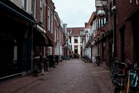 Calle de casas históricas de ladrillo con bicicletas aparcadas y un cartel de cerveza en el centro de Leeuwarden, Frisia