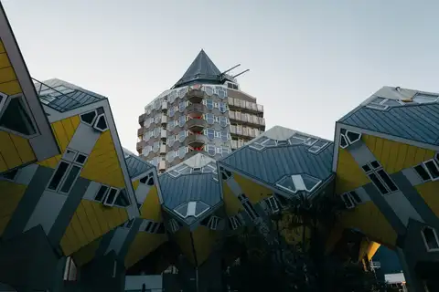 Casas cubo amarillas de Róterdam con el edificio Het Potlood de torre cónica al fondo bajo un cielo claro
