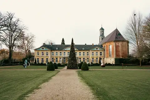 Palacio histórico de Valkenburg con un gran árbol de Navidad iluminado en el césped y un camino de grava en primer plano