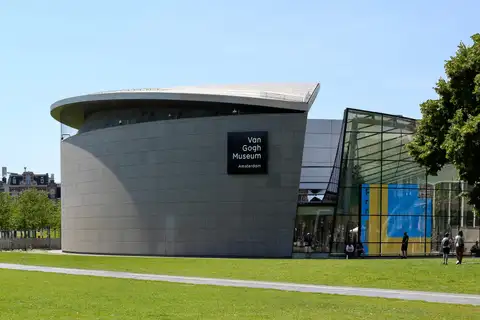 Fachada curva de granito y la entrada acristalada del Museo Van Gogh, con visitantes en el césped de la Museumplein