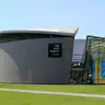 Fachada curva de granito y la entrada acristalada del Museo Van Gogh, con visitantes en el césped de la Museumplein
