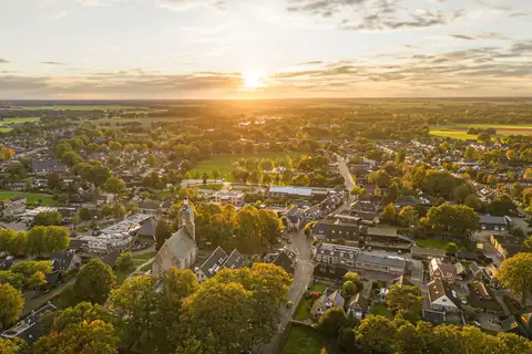 Vista aérea al atardecer del pueblo de Ruinen, en la provincia de Drenthe, con casas entre árboles y campos verdes