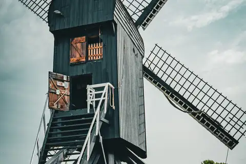 Molino de madera negro de Bourtange, en Groninga, con sus aspas y la escalera de acceso bajo un cielo nublado