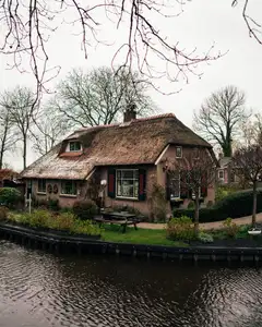Canal de Giethoorn con casas de ladrillo y tejados de junco, jardines cuidados y un puente de madera