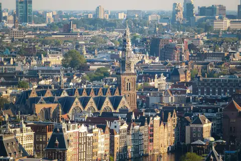 Vista elevada del centro de Ámsterdam con la torre de la Oude Kerk, tejados históricos y casas junto al canal