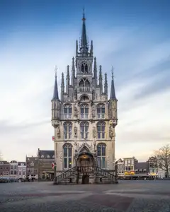 Ayuntamiento gótico exento de Gouda, con fachada de piedra y torrecillas, en la plaza del Markt bajo cielo nublado