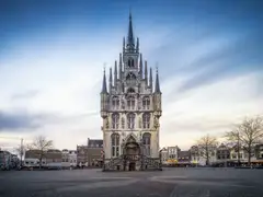 Ayuntamiento gótico exento de Gouda, con fachada de piedra y torrecillas, en la plaza del Markt bajo cielo nublado