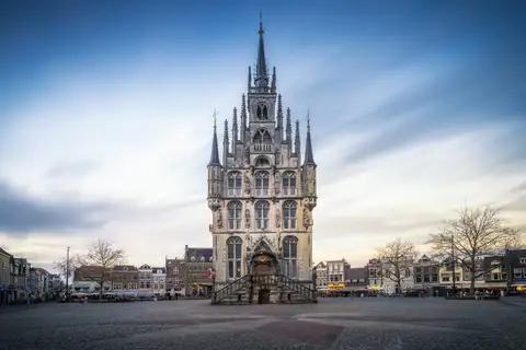 Ayuntamiento gótico exento de Gouda, con fachada de piedra y torrecillas, en la plaza del Markt bajo cielo nublado