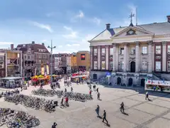 Grote Markt de Groninga con el ayuntamiento neoclásico, peatones y muchas bicicletas aparcadas en primer plano en un día soleado