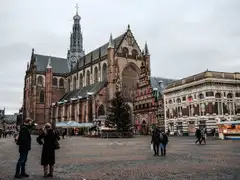 Fachada gótica de ladrillo de la iglesia de San Bavón en la Grote Markt de Haarlem, con peatones en la plaza adoquinada