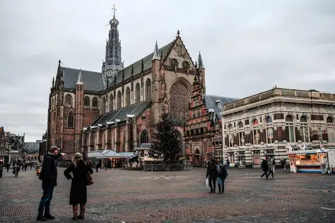 Fachada gótica de ladrillo de la iglesia de San Bavón en la Grote Markt de Haarlem, con peatones en la plaza adoquinada