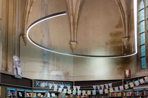 Librería Dominicanen de Maastricht instalada en una iglesia gótica, con estanterías de libros infantiles bajo bóvedas de piedra y un aro de luz