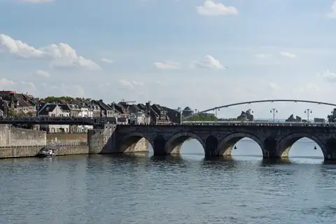 Puente histórico de piedra sobre el río Mosa en Maastricht, con la ciudad al fondo