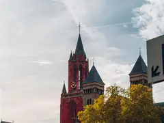 Torre roja de la iglesia de San Juan y las torres románicas de la basílica de San Servacio sobre los árboles otoñales del Vrijthof, Maastricht