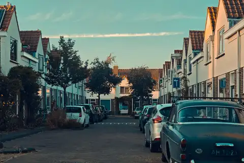 Calle residencial adoquinada de Utrecht con casas de ladrillo y tejados rojos, coches aparcados y un Volvo clásico en primer plano