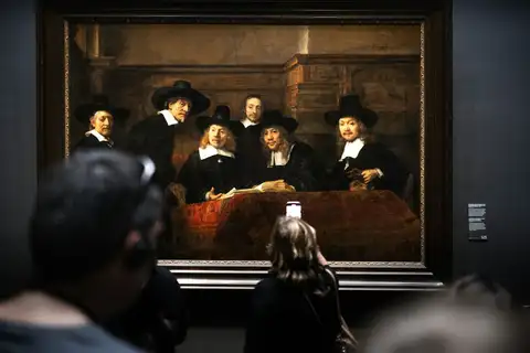 Visitantes de espaldas ante Los síndicos del gremio de pañeros de Rembrandt, colgado en una sala del Rijksmuseum de Ámsterdam