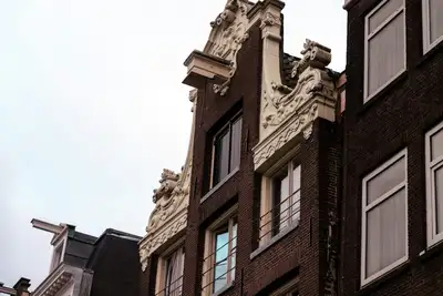 Fachadas de ladrillo oscuro con gablete decorado de piedra clara y viga de polea de casas de comerciantes históricas de Ámsterdam