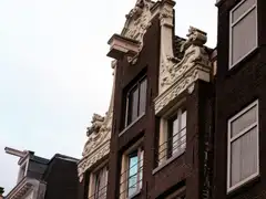 Fachadas de ladrillo oscuro con gablete decorado de piedra clara y viga de polea de casas de comerciantes históricas de Ámsterdam