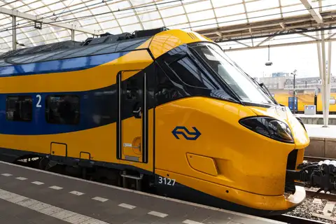 Tren NS moderno amarillo y azul detenido en un andén bajo la cubierta de cristal de una estación de Ámsterdam