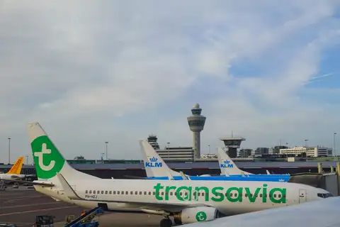 Aviones de Transavia y KLM estacionados en el aeropuerto de Ámsterdam-Schiphol, con la torre de control al fondo