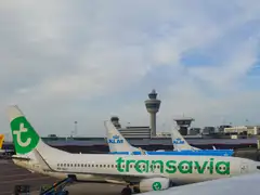 Aviones de Transavia y KLM estacionados en el aeropuerto de Ámsterdam-Schiphol, con la torre de control al fondo